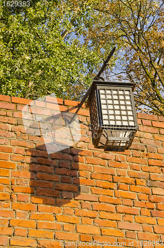Image of Ancient illuminator mounted on red brick wall. Oldtown details. 
