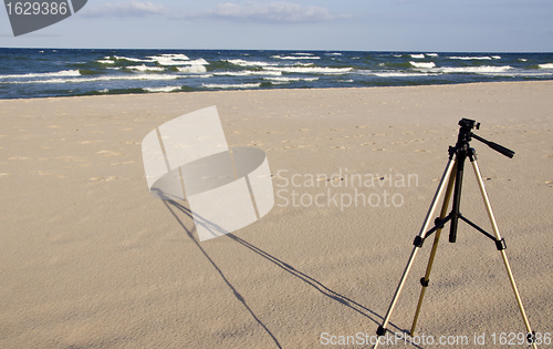 Image of Camera tripod standing in the seasand. 