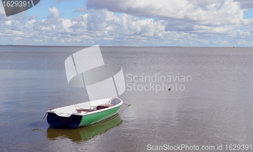 Image of Lonely plastic boat tied near quiet lake shore. 