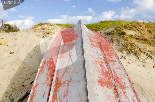 Image of Boat made of tin upside down resting on the dunes.