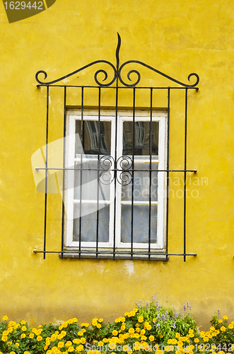 Image of House window with a decorative protective grating. Yellow wall. 