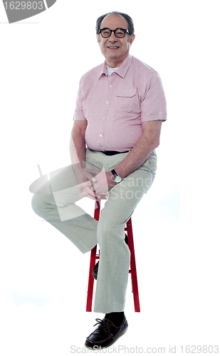 Image of Confident senior man resting on stool