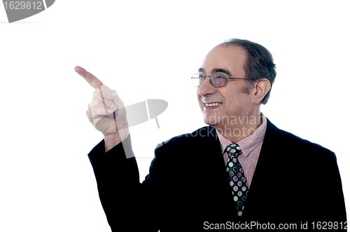 Image of Senior smiling director pointing away