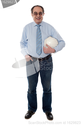 Image of Senior architect holding hard-hat, full length