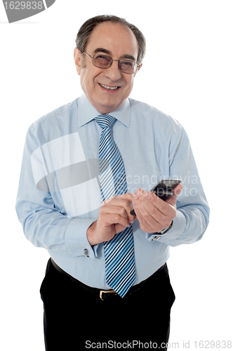 Image of Smiling elder business executive texting