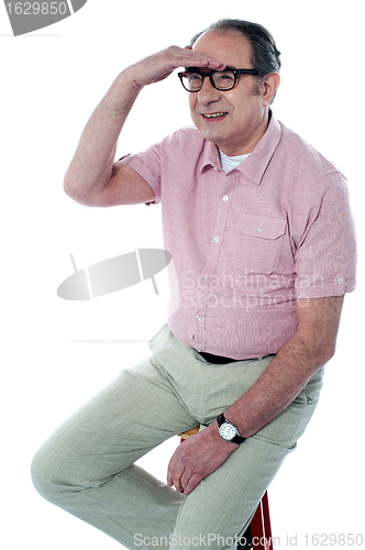 Image of Seated handsome old man looking far away by