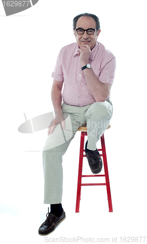 Image of Confident senior man resting on stool