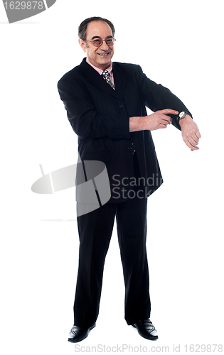 Image of Senior businessman pointing towards wrist watch