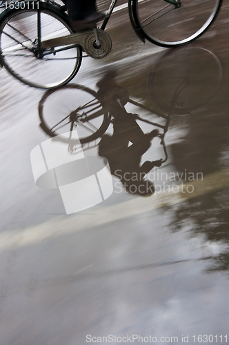 Image of Man on bicycle in puddle reflection