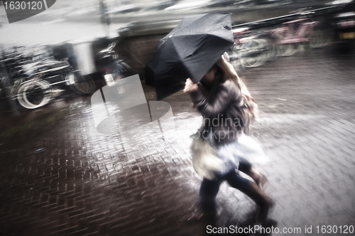 Image of Two women under umbrella in rain and wind