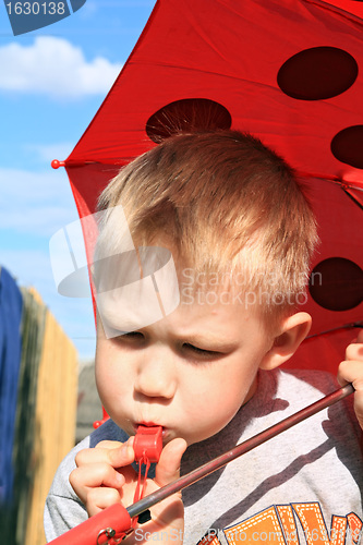 Image of small boy under red umbrella