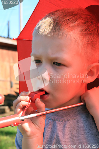 Image of small boy under red umbrella