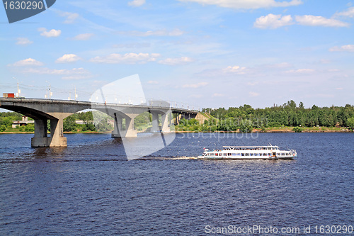 Image of small promenade motor ship on big river near bridge