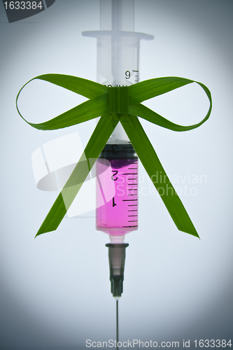 Image of syringe pink liquid with ribbon of grass
