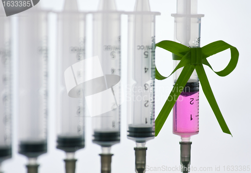 Image of syringes pink liquid with ribbon of grass