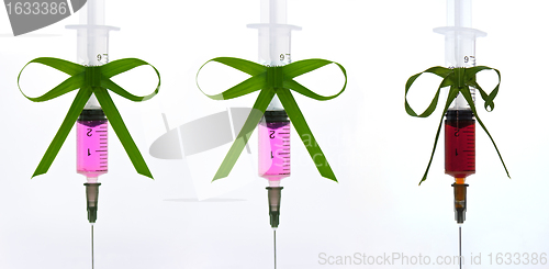 Image of syringes pink liquid with ribbons of grass