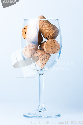 Image of single glass wine with a corks of bottle