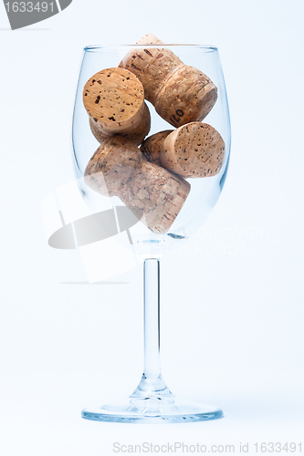 Image of single glass wine with a corks of bottle