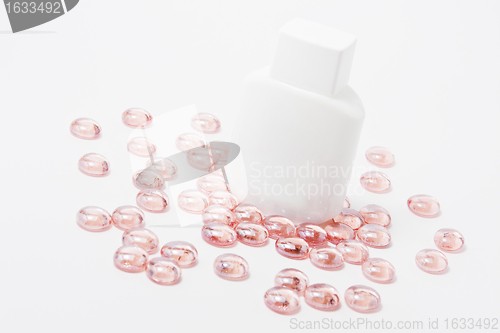 Image of white container for cosmetics on pink glass stones