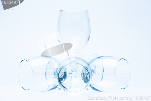 Image of Wine glasses stand and lie symmetrically on white