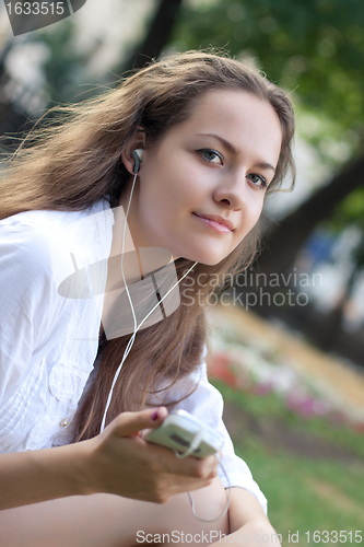 Image of young woman listens to music in ear-phones