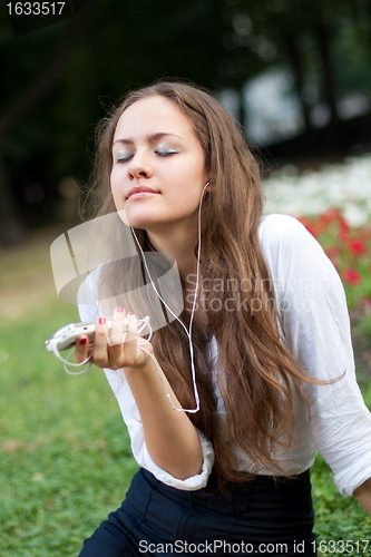 Image of young woman listens to music in ear-phones