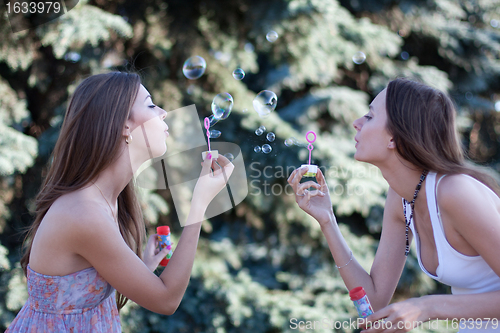 Image of Two young women make soap bubbles