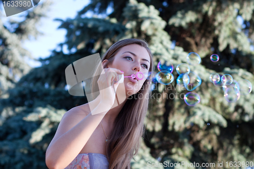 Image of young woman makes soap bubbles