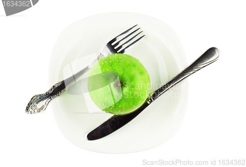 Image of fork, knife, green apple on white dish
