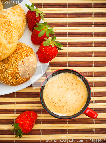 Image of coffee, buns and strawberries on table