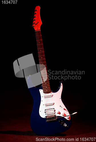 Image of electric guitar in ray of red light