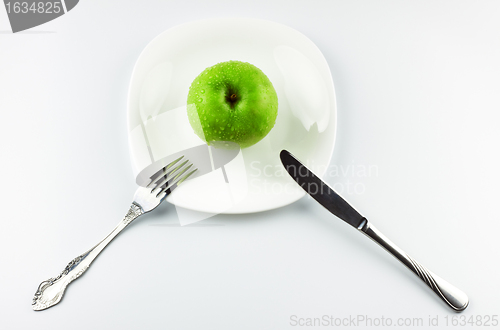 Image of fork, knife, green apple on white dish