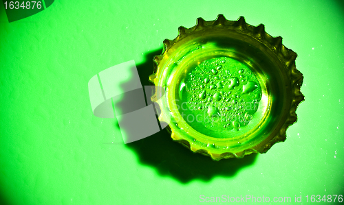 Image of beer cap with water drops on green