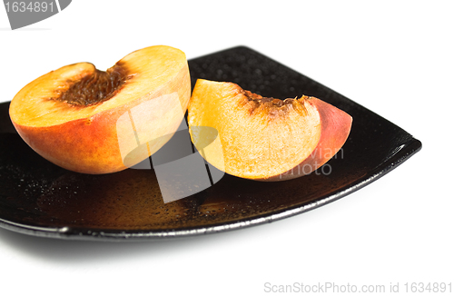 Image of red peaches slices on black dish