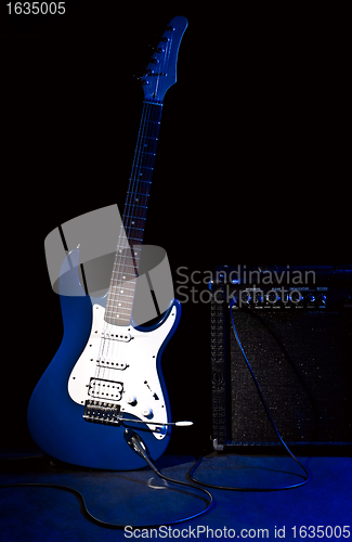 Image of electric guitar and combo amplifier in rays of blue light