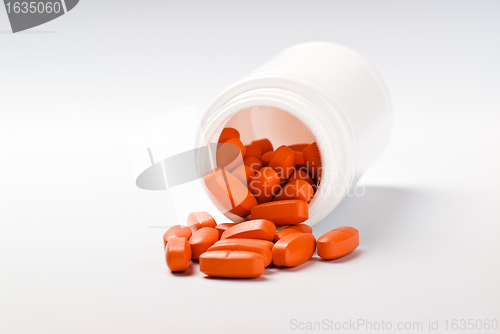 Image of orange pills spilling from bottle