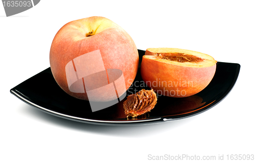 Image of red peaches with pip on black dish
