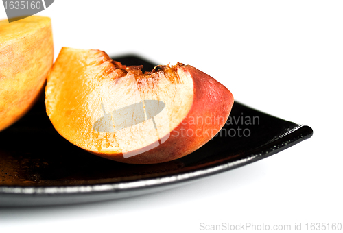 Image of red peaches slices on black dish