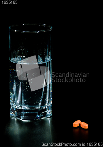 Image of two pills and glass of water