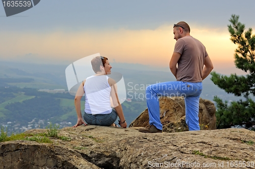 Image of Man and woman on the top of the mountain at sunset