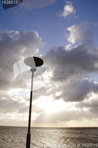 Image of park lamp on background of cloudy sky and sunlight 