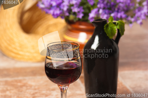 Image of Black jug for wine and a glass of red wine 