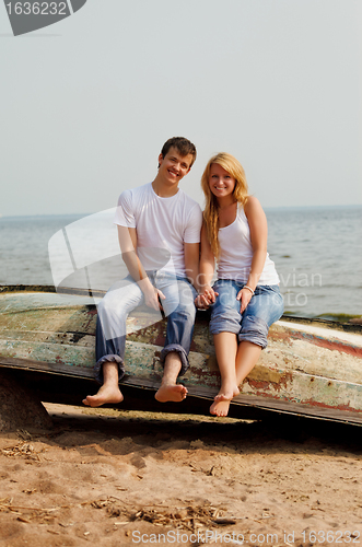 Image of couple on a beach sitting on old boat