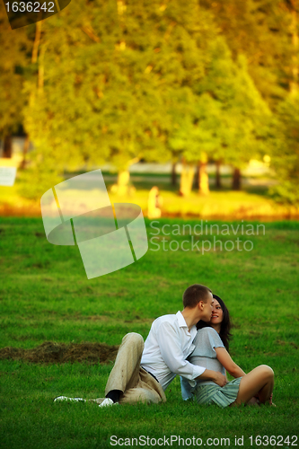 Image of young couple sitting on park lawn