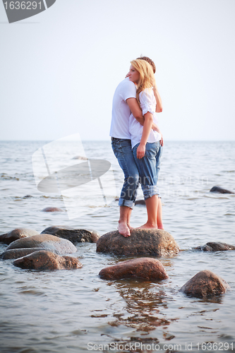 Image of couple embrace on a stone in sea