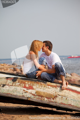 Image of couple sitting on old boat and kiss