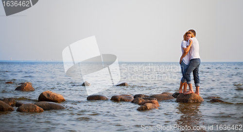 Image of couple embrace on a stone in sea