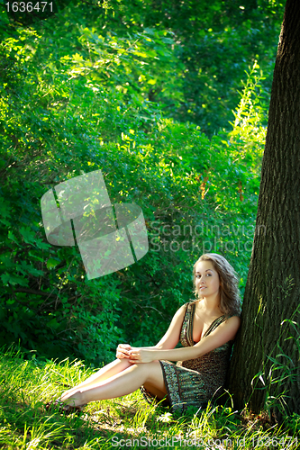 Image of beautyful woman sitting next tree