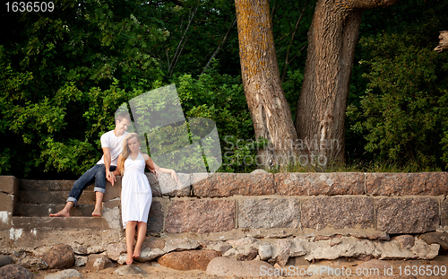 Image of couple stand next stonewall in forest