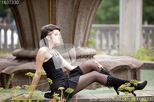 Image of girl in gothic style near old fontane